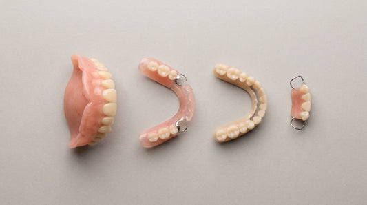 Four removable denture types side by side: a full upper denture, two partial dentures and a small single-sided partial